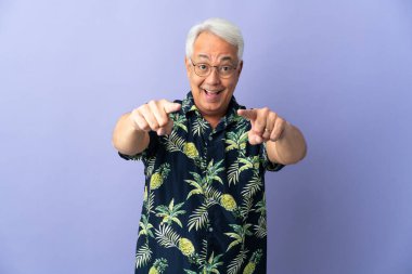 Mor arka planda izole edilmiş orta yaşlı Brezilyalı adam şaşırmış ve ön tarafı işaret ediyor.