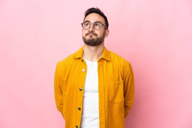 Beyaz tenli yakışıklı adam pembe arka planda izole edilmiş ve yukarı bakıyor.