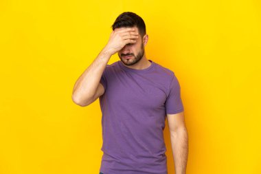 Sarı arka planda yalnız ve başı ağrıyan beyaz, yakışıklı bir genç.