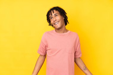 Sarı arka planda izole edilmiş, gülümseyen genç Afrikalı Amerikalı adam.