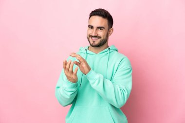 Beyaz tenli yakışıklı adam pembe arka planda izole edilmiş bir konferansta sunumdan sonra alkışlıyor.