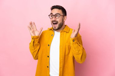 Pembe arka planda yalıtılmış beyaz, yakışıklı, şaşırtıcı bir yüz ifadesi olan genç adam.