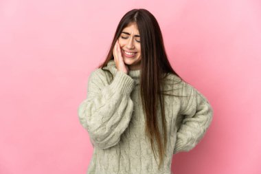 Pembe arka planda izole edilmiş, diş ağrısı olan beyaz bir kadın.