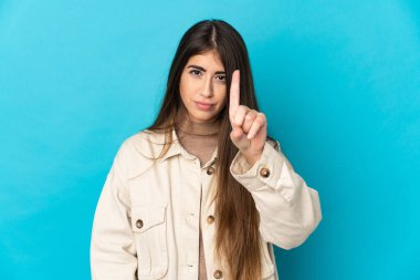 Mavi arka planda izole edilmiş beyaz bir kadın ciddi bir ifadeye sahip birini sayıyor