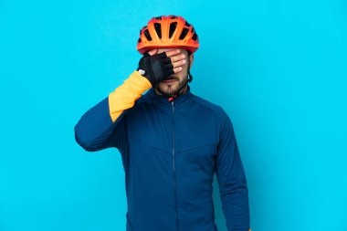 Genç bisikletçi mavi arka planda tek başına, gözleri elle kapatıyor. Bir şey görmek istemiyorum.