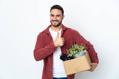 Beyaz arka planda izole edilmiş eşyalarla dolu bir kutuyu kaldırırken beyaz bir adam harekete geçiyor.