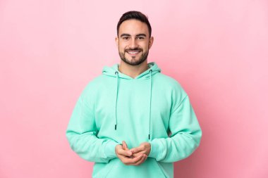 Beyaz tenli yakışıklı adam pembe arka planda izole edilmiş gülüyor.