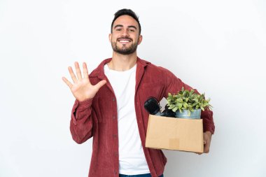 Beyaz arka planda izole edilmiş eşyalarla dolu bir kutuyu alırken beyaz adam hamle yapıyor. Parmaklarıyla beşi sayıyor.