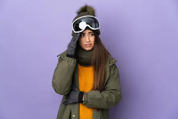 滑雪者高加索女孩与雪板眼镜隔离紫色背景与头痛 — 图库照片