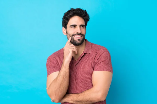 Joven Hombre Guapo Con Barba Sobre Fondo Azul Aislado Pensando — Foto de Stock