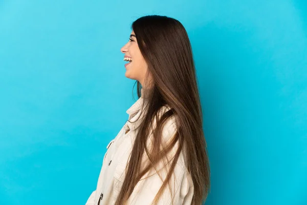 Giovane Donna Caucasica Isolata Sfondo Blu Ridendo Posizione Laterale — Foto Stock