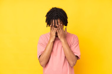 Genç Afrikalı Amerikalı adam sarı arka planda izole edilmiş, yorgun ve hasta bir ifadeyle.