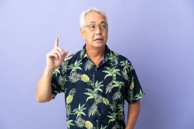 Mor arka planda izole edilmiş orta yaşlı Brezilyalı bir adam, bir fikrin işaret ettiğini düşünüyor.