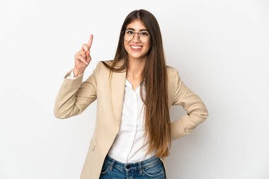 Beyaz arka planda izole edilmiş genç beyaz kadın en iyinin işareti olarak parmağını kaldırıyor ve gösteriyor.