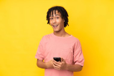 Sarı arka planda izole edilmiş genç bir Afrikalı Amerikalı şaşırdı ve bir mesaj gönderiyor.