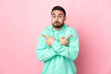 Pembe arka planda izole edilmiş beyaz, yakışıklı genç adam, yan taraftakilerin kuşkuları olduğunu gösteriyor.