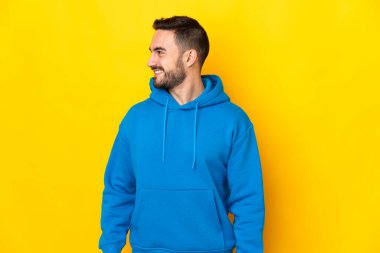 Sarı arka planda izole edilmiş beyaz, yakışıklı genç bir adam.