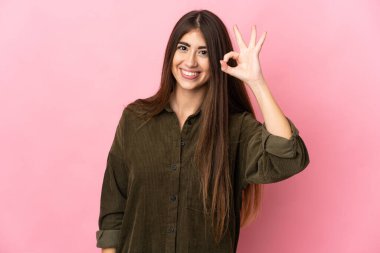 Pembe arka planda izole edilmiş beyaz bir kadın parmaklarıyla tamam işareti gösteriyor.