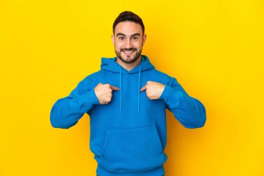 Sarı arka planda yalıtılmış, yüzü şaşırmış, beyaz, yakışıklı genç bir adam.