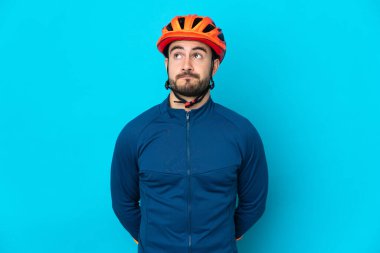 Genç bisikletçi mavi arka planda izole edilmiş ve yukarı bakıyor.