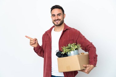 Beyaz arka planda izole edilmiş eşyalarla dolu bir kutuyu kaldırırken beyaz bir adam hareket ediyor.