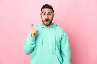 Pembe arka planda soyutlanmış beyaz, yakışıklı bir adam çözümü bulmak için parmağını kaldırıyor.