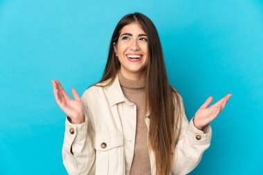 Mavi arka planda izole edilmiş genç beyaz kadın çok gülümsüyor.