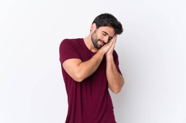 Sakallı, beyaz arkaplanlı yakışıklı genç adam hareketli bir uyku hareketi yapıyor.