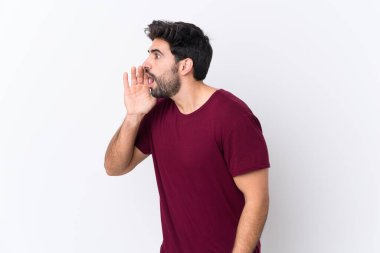 Sakallı yakışıklı bir genç beyaz arka planda ağzı sonuna kadar açık bağırıyor.