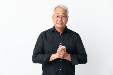 Orta yaşlı Brezilyalı bir adam beyaz arka planda yalnız gülüyor.