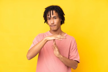 Genç Afrikalı Amerikalı adam sarı arka planda izole edilmiş.