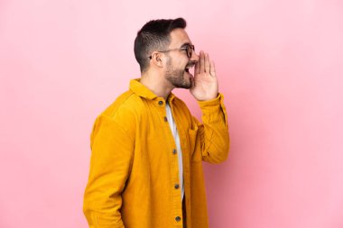 Pembe arka planda izole edilmiş, ağzı sonuna kadar açık bağıran beyaz, yakışıklı genç bir adam.