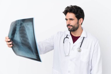 Sakallı, beyaz bir geçmişi olan, doktor önlüğü giymiş ve elinde kemik taraması yapan yakışıklı bir genç.