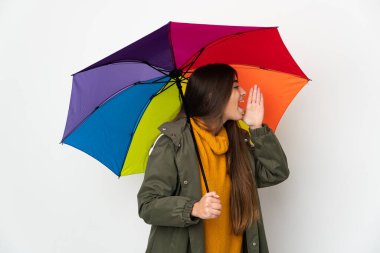 Beyaz arka planda izole edilmiş bir şemsiye tutan genç bir kadın ağzı sonuna kadar açık bağırıyor.