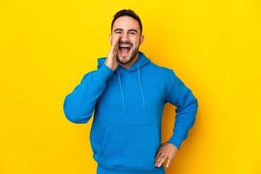 Sarı arka planda izole edilmiş, ağzı açık genç beyaz adam bağırıyor.