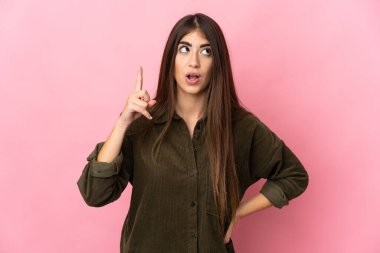 Pembe arka planda izole edilmiş genç beyaz kadın çözümü bulmak için parmağını kaldırıyor.