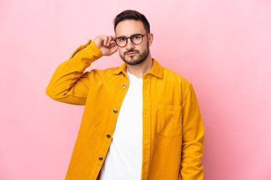 Pembe arka planda izole edilmiş beyaz, yakışıklı genç bir adam. Şüpheleri var.