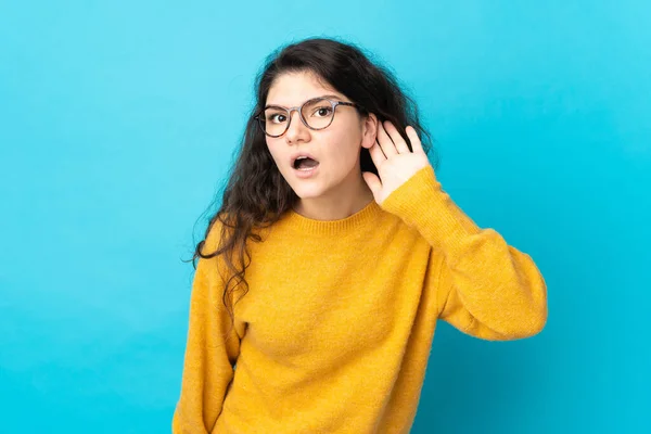 Tiener Russisch Meisje Geïsoleerd Blauwe Achtergrond Luisteren Naar Iets Door — Stockfoto