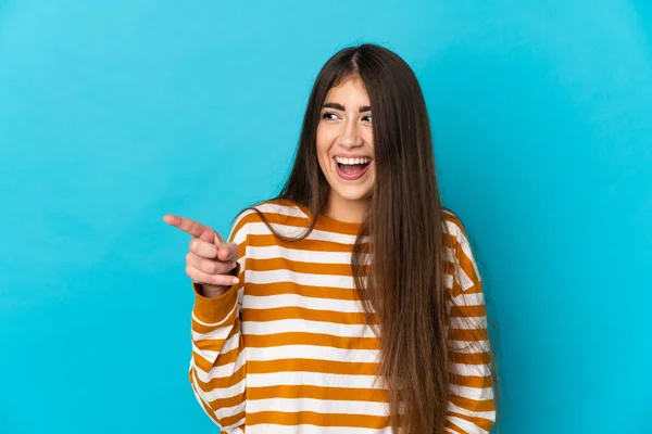 青い背景の指を横に向けて商品を発表する若い白人女性 — ストック写真