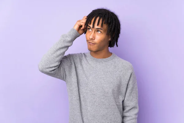 若いアフリカ系アメリカ人の男性は紫の背景に疑いを持ち 顔の表情を混乱させる — ストック写真
