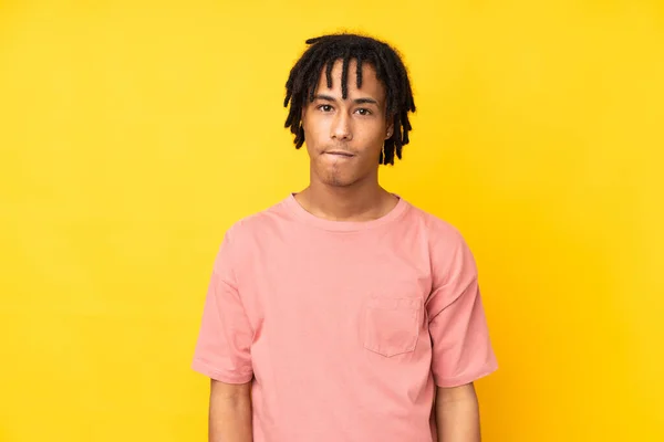 黄色の背景に孤立した若いアフリカ系アメリカ人男性は 顔の表情を混乱させ — ストック写真