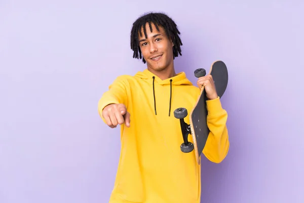 年轻的非洲裔美国人 身披紫色背景 头戴溜冰鞋 指着前方 — 图库照片
