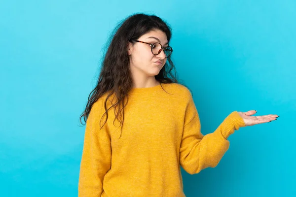 Adolescente Russo Menina Isolado Fundo Azul Segurando Copyspace Com Dúvidas — Fotografia de Stock