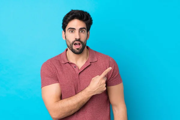 Jovem Homem Bonito Com Barba Sobre Fundo Azul Isolado Surpreendido — Fotografia de Stock