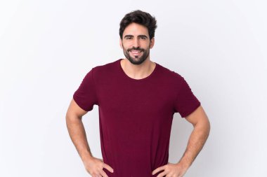 Sakallı yakışıklı bir genç soyutlanmış beyaz bir geçmişi var. Kolları kalçasında ve gülümsüyor.