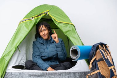 Genç Afro-Amerikan bir adam kamp yeşil çadırında en iyinin işareti olarak parmağını kaldırıyor.