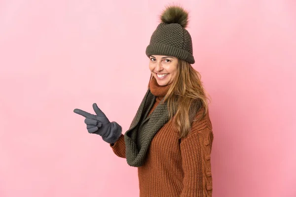 Mulher Meia Idade Com Chapéu Inverno Isolado Fundo Rosa Apontando — Fotografia de Stock
