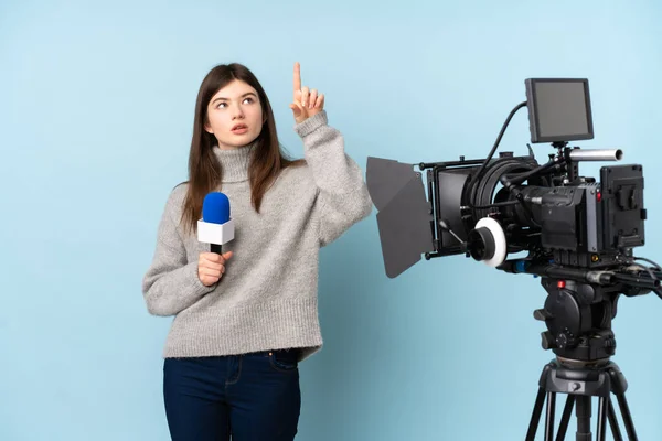 Young reporter woman holding a microphone and reporting news touching on transparent screen