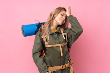 Pembe arka planda izole edilmiş büyük sırt çantalı genç Rus dağcı kız bir şey fark etti ve çözüme niyetlendi.