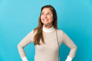 Genç tele pazarlamacı kadın mavi arka planda bir fikir ararken...